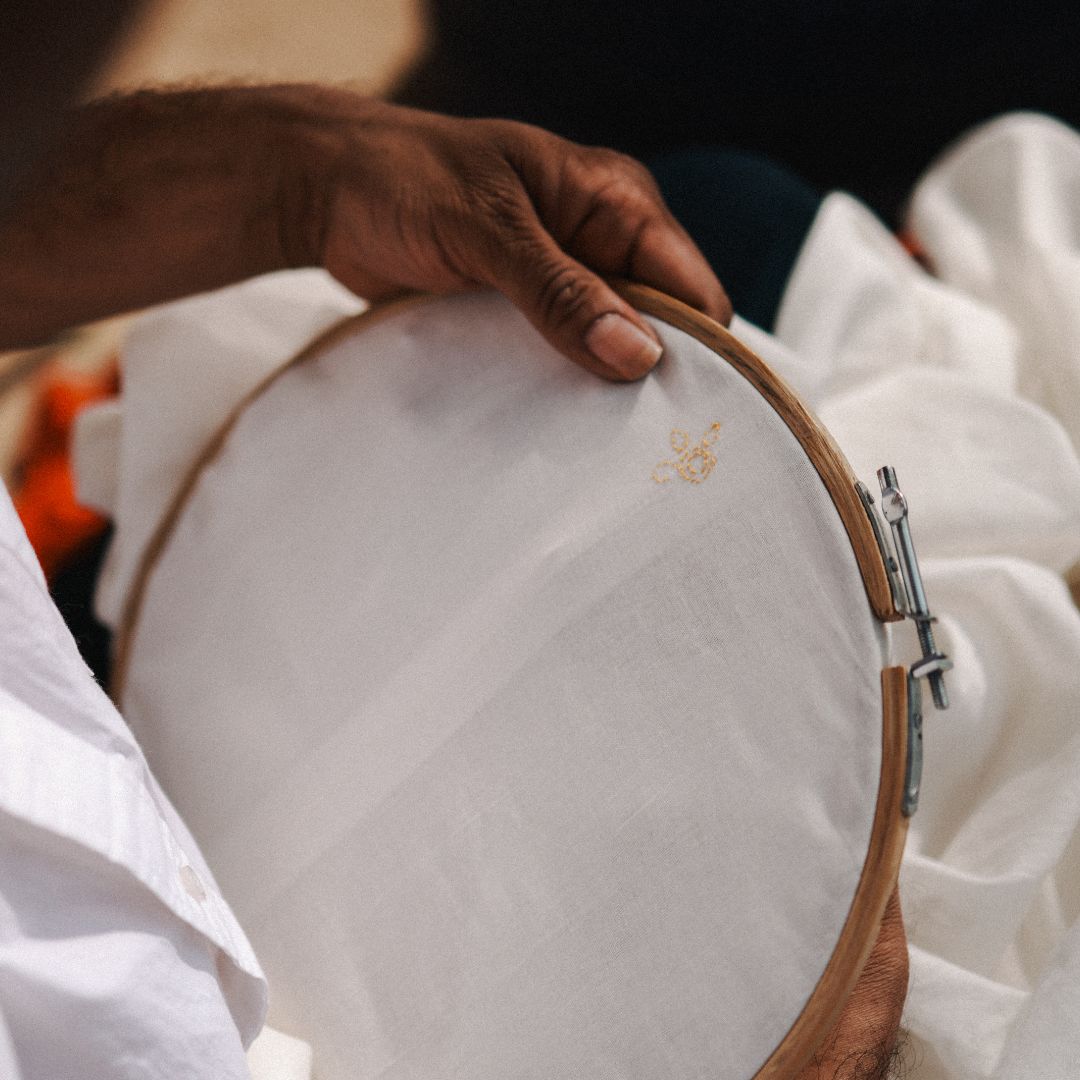 Person holding a white fabric with a wooden embroidery hoop